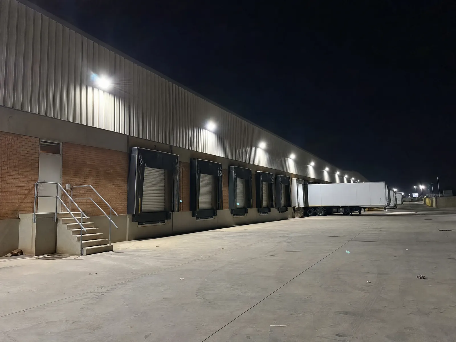 Exterior LED floodlighting over loading docks at a logistics warehouse at night
